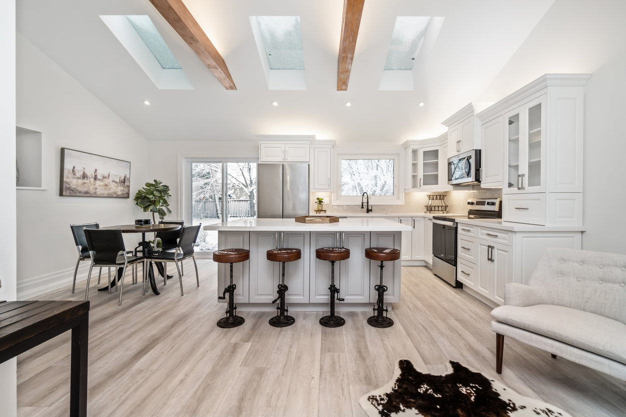 Pinewood kitchen with white cabinetry, wood beams and finished flooring